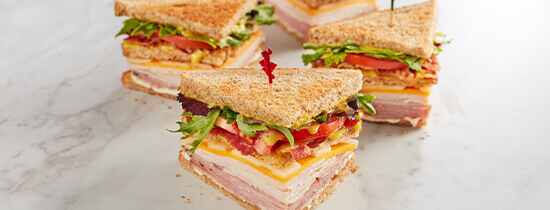 3 deluxe club sandwiches sliced in triangles with toothpicks in each slice. 