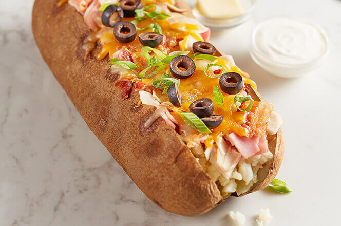 A Spud Max baked potato with ham, turkey, bacon, cheddar cheese, and sour cream.