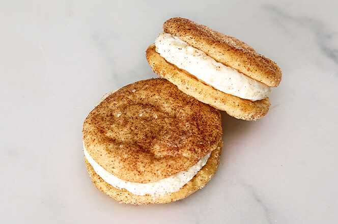 Two cookie sandwiches filled with icing and displayed on a plate.