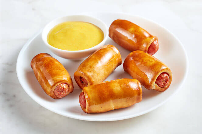 Mini pretzel dogs with a side of mustard dipping sauce.