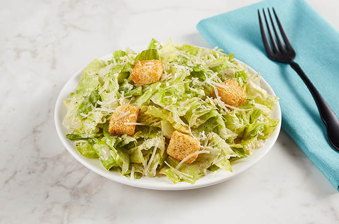 A side Caesar salad with crisp romaine, shredded Parmesan, and croutons.