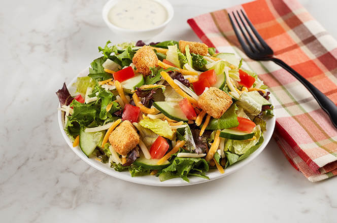 A side garden salad with mixed greens, tomatoes, cucumbers, and shredded carrots.