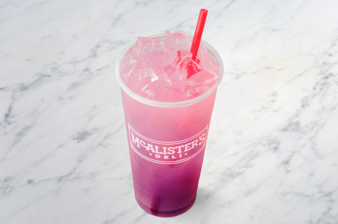 A cup of pink lemonade flavored party punch with ice and a pinkish-purple hue.