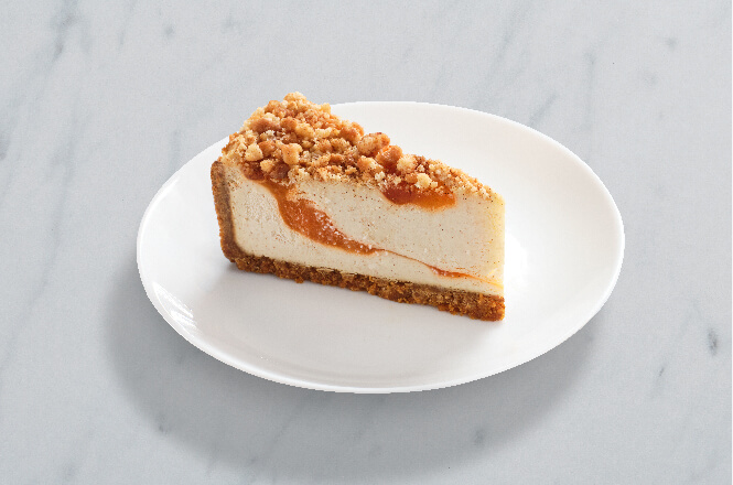 A slice of peach cobbler cheesecake topped with peach slices and streusel.