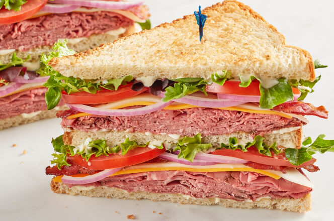 A Black Angus King Club triple-decker sandwich with roast beef, bacon, cheddar, Swiss, lettuce, tomato, and horseradish sauce.