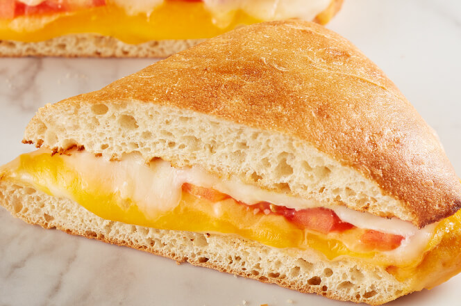 A Four Cheese Melt sandwich with gooey layers of cheddar, Swiss, provolone, and Parmesan cheeses on toasted bread.