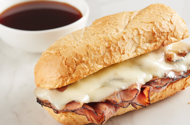 A 6-inch French Dip sub sandwich with roast beef and melted Swiss cheese on a toasted baguette, served with au jus for dipping.