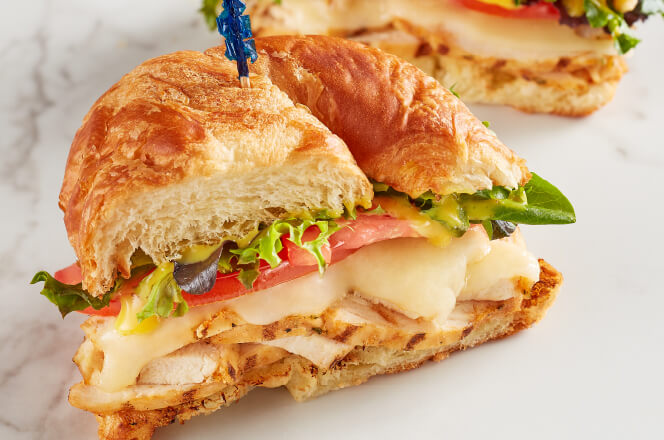 A Grilled Chicken Sandwich on croissant bread with chicken, lettuce, tomato, and honey mustard.