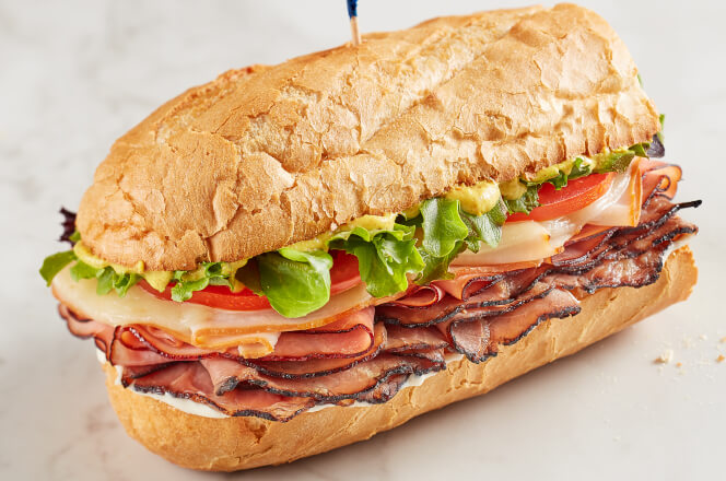 A Memphian sub sandwich with turkey, ham, roast beef, provolone cheese, lettuce, tomato, and mayonnaise on toasted bread.