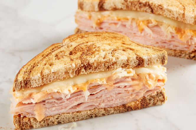 A turkey sandwich with Swiss cheese, sauerkraut, and Thousand Island dressing on toasted rye bread.