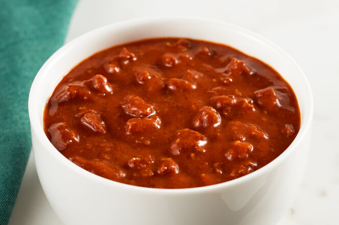 A bowl of meaty chili topped with shredded cheese and green onions.